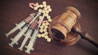 Narcotics concept, judge's gavel with drugs and syringes on wood