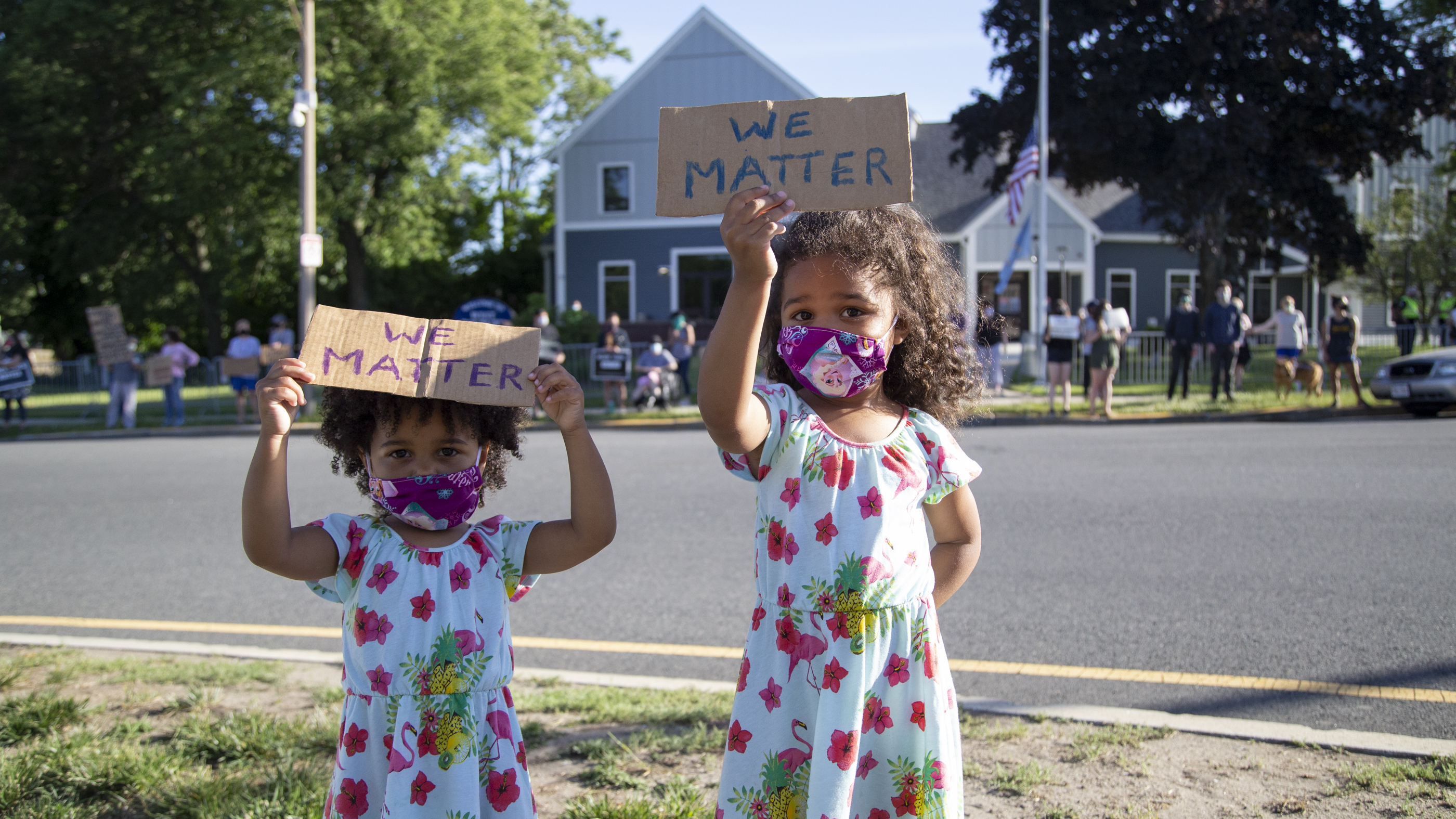 Two girls hold up signs at a Black Lives Matter vigil in West Roxbury