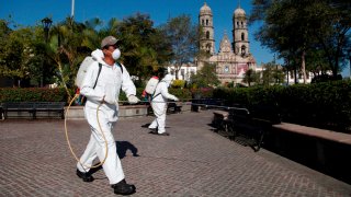 Hombres fumigan un parque en Zapopan