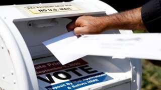 A voter drops a ballot into the box for mail-in ballots