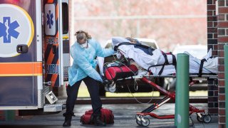 In this April 17, 2020, file photo, a first responder wheels a COVID-19 patient into an ambulance in Chelsea, Massachusetts.