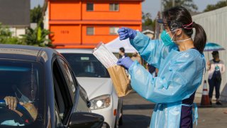 Health worker Hannah Kwon explains to a individual in car, on how to use oral swabs at a drive-thru COVID-19 test site