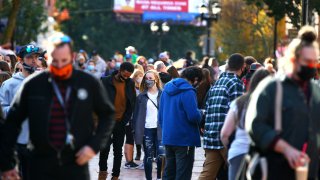 Crowds walk through a Salem, Mass., street wearing masks.