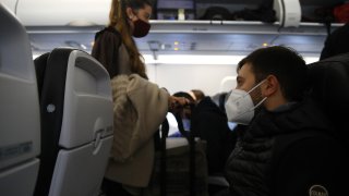 Passengers take their seats for a flight wearing protective masks