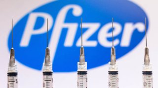 In this file photo illustration, various medical syringes seen with Pfizer company logo displayed on a screen in the background.