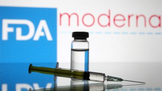 A vial and a medical syringe sit in front of an FDA sign.