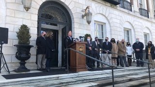 Governor Ned Lamont stands at podium outside white stone building