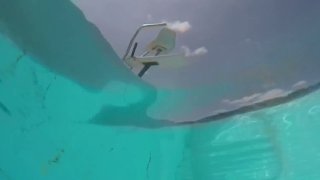 An empty lifeguard chair seen through pool water