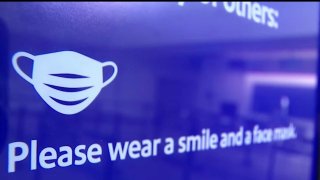 Face mask graphic on blue sign at an airport