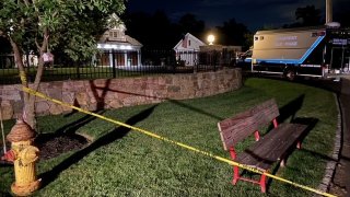 police tape in the foreground with a while van. There is blue text that reads Connecticut State Police on the van.