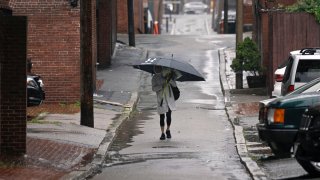 A person carries an umbrella walking down an alleyway