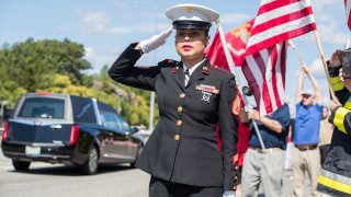 U.S. Marine SSgt. Alice Ward stands at attention on the side of I-93 North as the hearse carrying fallen Marine Sgt. Johanny Rosario Pichardo passes Stoneham on Saturday Sept. 11, 2021.