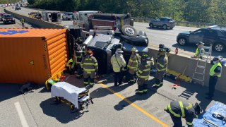 Firefighters work to free a driver after a truck crash on the Massachusetts Turnpike