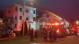 A ladder truck with ladder extended to a wood multi-family home