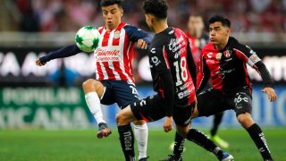 Tres jugadores de fútbol disputan un balón