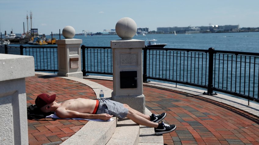 BOSTON – JULY 27: A man naps in the sun at the edge of Piers Park as temperatures soar on a hot day in East Boston on July 27, 2020. (Photo by Jessica Rinaldi/The Boston Globe via Getty Images)