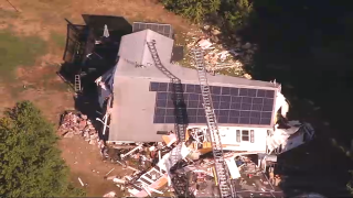 A house in New Hampshire is shown to be torn apart as fire crews work on scene