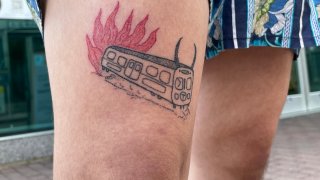 A tattoo of an Orange Line train, complete with horns, on fire.