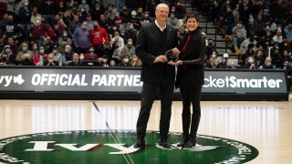 This March 12, 2022, file photo shows Massachusetts Gov. Charlie Baker being presented with an award by Harvard University Director of Athletics Erin McDermott to honor him for the Class of 2022 Legends of Ivy League Basketball during the Ivy League Tournament semifinal between the Pennsylvania Quakers and Yale Bulldogs at Lavietes Pavilion in Boston's Allston neighborhood.