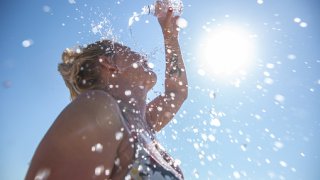 A young woman cools down with cold water during the summer heat.