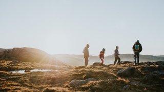 A young family enjoy the view from the top of a mountain
