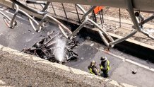 Firefighters spraying the charred wreckage of a vehicle in Boston by Widett Circle on Wednesday, June 5, 2024.