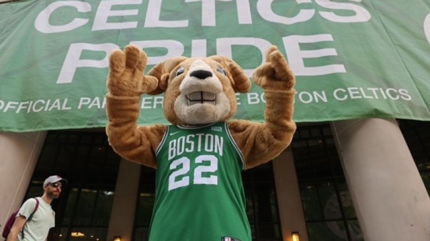 A goat mascot in a Celtics jersey in front of a "CELTICS PRIDE" sign hanging on a building in Boston before the championship parade Friday, June 21, 2024.