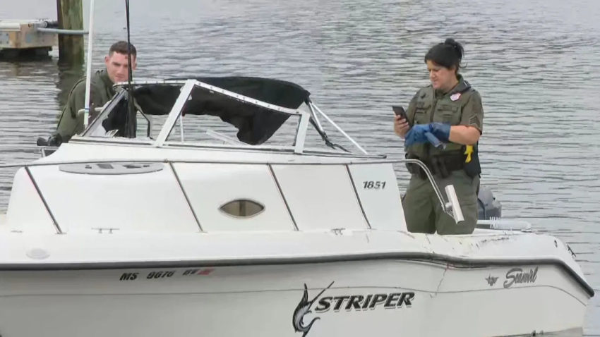 DEM officers inspecting damage to the smaller boat (WJAR)