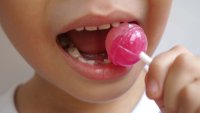 Boy kid consuming sweet candy lollipop with sugar added, causing loss teeth and unhealthy oral care. closeup photo, blurred.