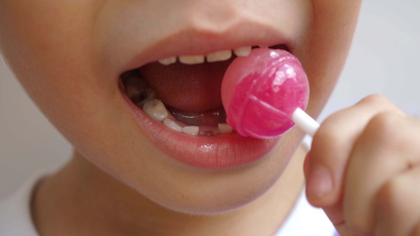 Boy kid consuming sweet candy lollipop with sugar added, causing loss teeth and unhealthy oral care. closeup photo, blurred.