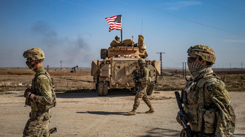 TOPSHOT – Soldados estadounidenses caminan mientras patrullan junto a los campos petrolíferos de Suwaydiyah, en la provincia nororiental siria de Hasakah, el 13 de febrero de 2021. (Foto de DELIL SOULEIMAN / AFP) (Foto de DELIL SOULEIMAN/AFP vía Getty Images)