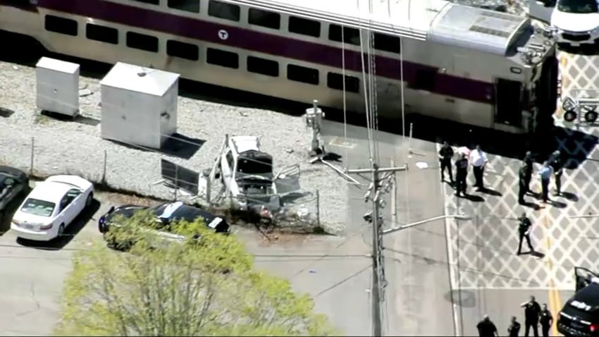 The scene of a train crash in Abington, Massachusetts, on April 30, 2025. A damaged, while car can be seen near the stopped train.