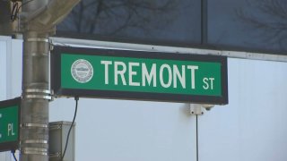 A closeup of a street sign, green with white text, that reads "TREMONT ST."