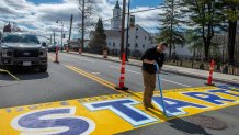 Painter Frankie Dinardi of New Hampshire-based Mission Turf Services lifts the last pieces of tape at the painting of the 129th Boston Marathon start line in Hopkinton on Tuesday, April 16, 2025.