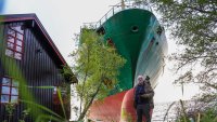 Johan Helberg poses next to his house and a 135-meter-long container ship by the shore in the Trondheimsfjord outside Byneset by Trondheim, Norway, on May 22, 2025, after the ship ran aground almost hitting his house. (Photo by Jan Langhaug / NTB / AFP) / Norway OUT (Photo by JAN LANGHAUG/NTB/AFP via Getty Images)