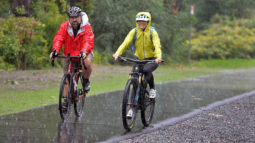 Joel Barrera, of Natick, Cochituate Rail Trail Advisory Committee, and Alexi Conine, of Boston, arrive in the rain for the official Mass. DOT ribbon cutting ceremony of the Framingham-Natick Rail Trail, September 28, 2021.