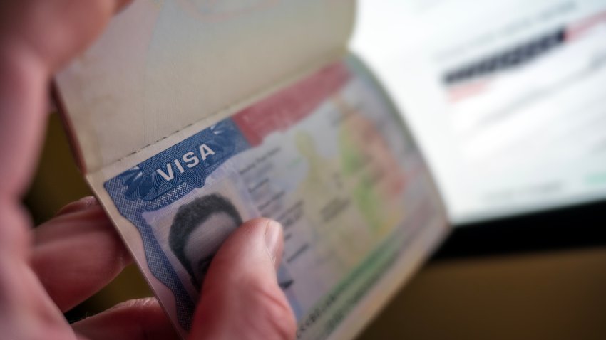 Unknown causian person holding passport with visa issued for United States of America